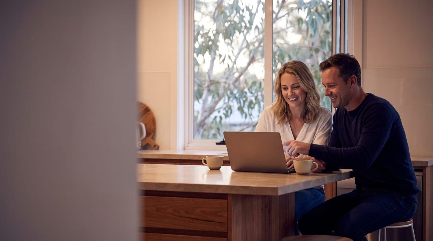 A couple at their kitchen bench discovering what refinancing could save them